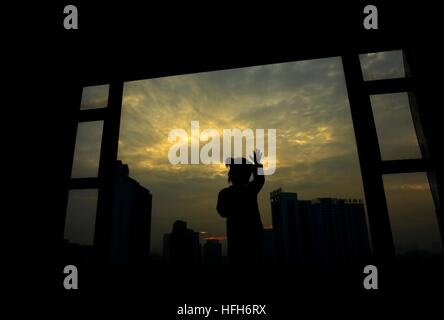 Qinzhou cinese di Guangxi Zhuang Regione autonoma. 1a gen, 2017. Una ragazza opinioni il sunrise a casa in Qinzhou, sud della Cina di Guangxi Zhuang Regione autonoma, 1 gennaio, 2017. © Lin Hong/Xinhua/Alamy Live News Foto Stock