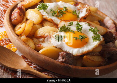 Paese cucina: patate fritte con carne, uova e bacon close-up in una ciotola di legno orizzontale. Foto Stock