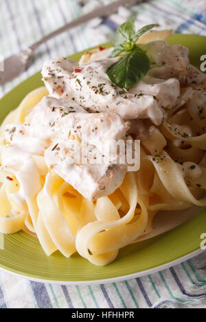 Italian fettuccine con pollo e salsa alla panna close-up su una piastra verticale. Foto Stock