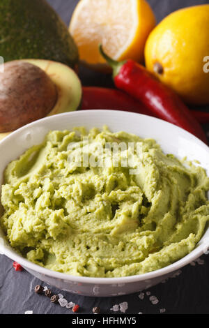 Verde messicano guacamole salsa in una ciotola macro. In verticale Foto Stock