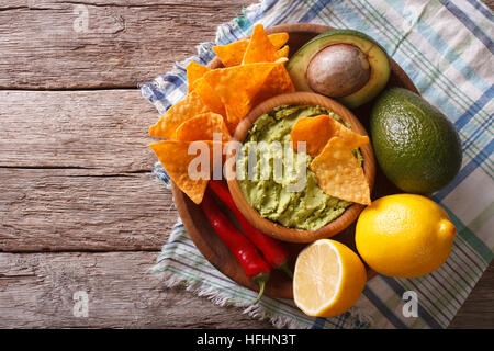 Corn chips, hot salsa guacamole e gli ingredienti sul tavolo. orizzontale vista superiore Foto Stock