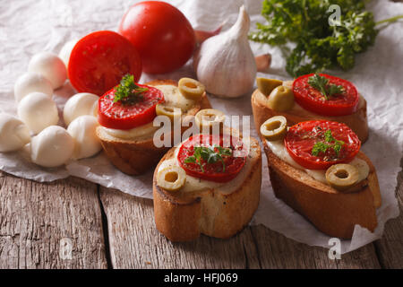 Bruschetta con pomodori, olive e formaggio vicino sul tavolo orizzontale. Foto Stock