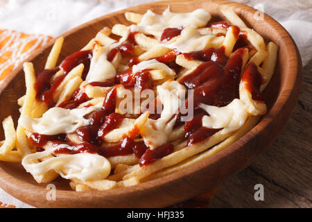 Poutine con salsa di formaggio e macro sul tavolo. Posizione orizzontale Foto Stock