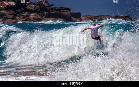 Un surfista salviette fuori su una grande onda alla spiaggia della balena. Surf rimane popolare in Australia nonostante un aumento di fata Foto Stock