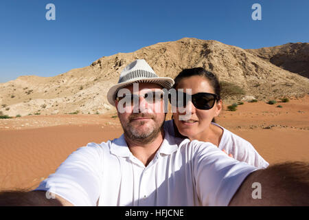 Coppia felice di 40 anni che scatta un selfie grandangolare nel deserto, catturando la loro avventura, la loro esperienza di viaggio e l'emozione Foto Stock