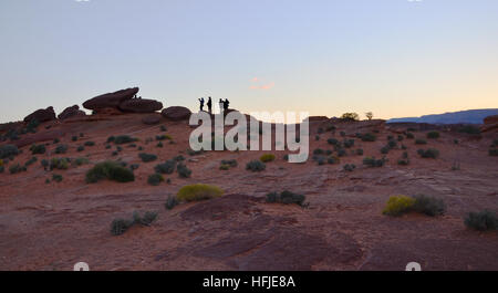 Silhouette di turisti sulla curva a ferro di cavallo, Arizona con molti cespugli e sabbia rossa sul tramonto Foto Stock