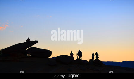 Silhouette di turisti sulla curva a ferro di cavallo, Arizona con molti cespugli e sabbia rossa sul tramonto Foto Stock