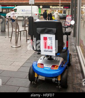 "L' Piastre pericolose driver donna segno di avvertimento sulla mobilità Scooter, trasporto disabili, alimentati a batteria, persona su sedia a rotelle, il pensionamento veicolo in Chapel Street, Southport, Merseyside, Regno Unito Foto Stock