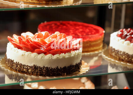 Diversi tipi di torte in una pasticceria display in vetro Foto Stock