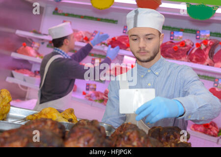 Macellaio di insegnamento di una giovane come vendere la carne Foto Stock