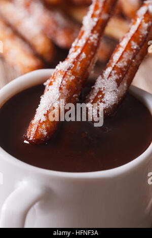 Churros tradizionale immerso in una tazza di salsa al cioccolato una macro verticale. Foto Stock