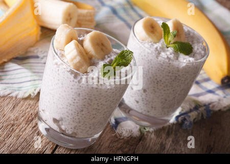 Cibo sano: pudding con semi di Chia e di banane fresche in un bicchiere vicino sul tavolo orizzontale. Foto Stock