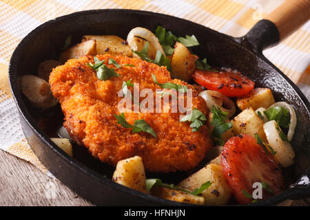 In casa tedesca panato Weiner schnitzel con verdure fritte in padella vicino sul tavolo orizzontale. Foto Stock
