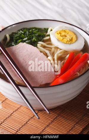 Ramen zuppa con carne di maiale, le verdure e le uova in una terrina close up verticale. Foto Stock