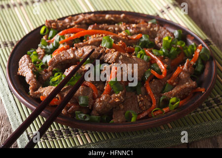 Cucina asiatica: fettine di carne fritti con sesamo e carota close-up su una piastra orizzontale. Foto Stock