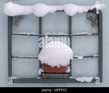 La vecchia cornice decorativa della finestra usata per l'arte del cortile è fringed con la neve Foto Stock