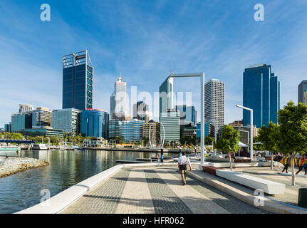 Lavoratore della città passeggiando lungo Elizabeth Quay con lo skyline della città al di là, Perth, Australia occidentale, Australia Foto Stock