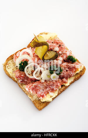 Condito di carne macinata di maiale su toast, guarnita con cipolla e spiedini di sottaceti Foto Stock