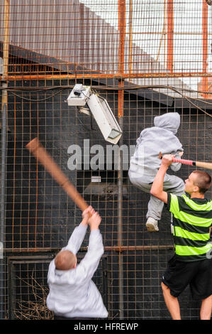 Il repubblicano giovani usare bastoni per rompere le telecamere TVCC in un recinto di sicurezza su un PSNI stazione di polizia Foto Stock