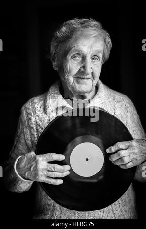 Donna anziana è in possesso di un disco in vinile. Foto in bianco e nero. Foto Stock