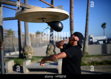 Giovane uomo a fare pratica con la boxe Speed bag sulla spiaggia di Venice, California. Foto Stock