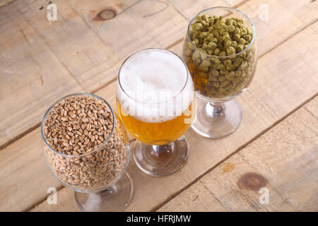 Bicchieri di birra di malto e luppolo su uno sfondo di legno Foto Stock