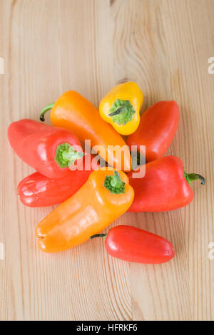 Un mucchio di coloratissimi mini peperoni su di un tavolo di legno. Foto Stock