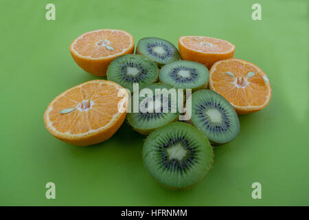 La vista di arance e kiwi catted su metà sulla superficie verde Foto Stock