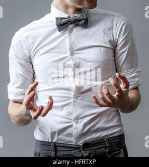 Uomo in una camicia bianca con un grigio il filtro bow tie. Aggressività e la rabbia dei gesti con le mani. Foto Stock