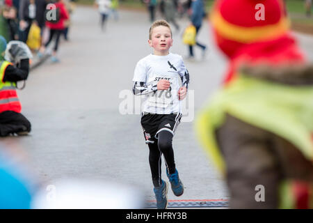 Nota dell'EDITORE: il permesso dei genitori dato Giuseppe Quinn, 8, attraversa la linea di arrivo a serpentina Capodanno 3k Fun Run in Hyde Park, Londra. Foto Stock