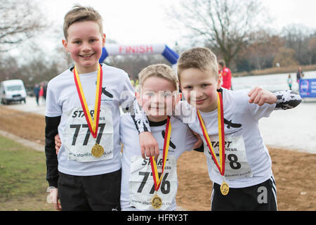 Nota dell'EDITORE: il permesso dei genitori dato (da sinistra a destra) fratelli Domenico, 10, Aidan, 6 e Joseph Quinn, 8, dopo aver attraversato la linea del traguardo a serpentina Capodanno 3k Fun Run in Hyde Park, Londra. Foto Stock