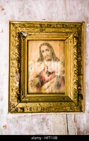 Molto vecchio Sacro Cuore immagine di Gesù Cristo si blocca su un muro sporco. Foto Stock