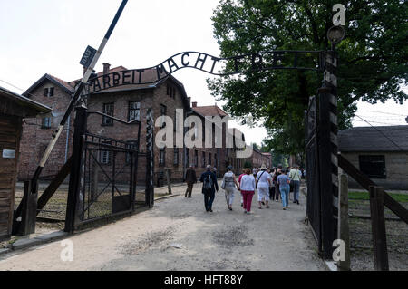 Visitatori di passaggio attraverso il Arbeit macht frei (lavoro porta libertà) cancello principale ingresso nella famigerata Auschwitz Birkenau campo di concentramento nazista i Foto Stock