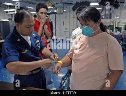 070629-N-4954I-015 a nord del Mar della Cina (29 giugno 2007) - Capo Hospital Corpsman Ron Palustre mette un braccialetto di identificazione medico su un filippino paziente come ella entra nel reparto di medicina di USS Peleliu (LHA 5). Ogni giorno fino a 20 persone sono volato per la spedizione tramite elicottero per il trattamento. Il personale medico è un team di statunitensi e stranieri medici militari in uniforme e civili di professionisti sanitari e organizzazione non governativa medici a bordo di Peleliu. Peleliu è unicamente in grado di supporto di assistenza medica e umanitaria ha bisogno ed è stata configurata con speciale medica Foto Stock