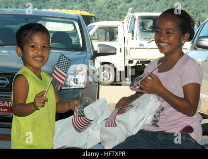 I bambini micronesiani sventolano bandiere americane durante un programma di azione civica medica presso l'edificio governativo della città di Lelu a Kosrae come parte della missione umanitaria Pacific Partnership. La missione fornisce assistenza medica, odontoiatrica e ingegneristica alle comunità del sud-est asiatico e dell'Oceania per un periodo di quattro mesi. Foto Stock