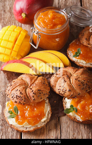 Panini con marmellata di mango, burro e decorate con menta fresca close up sul piano verticale. Foto Stock