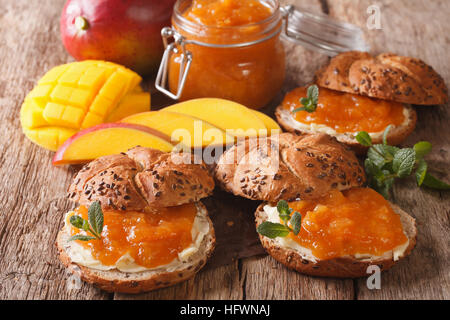 Panini saporiti con confettura di mango, burro e menta vicino sul tavolo orizzontale. Foto Stock