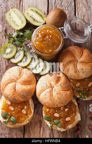 Panini dolci con burro e marmellata kiwi, menta e noccioline vicino sul tavolo. vista verticale da sopra Foto Stock