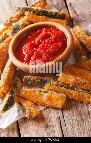 Gustoso antipasto: cotto bastoncini di zucchine impanati e piccante salsa di pomodoro closeup su una tavola verticale. Foto Stock