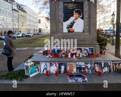 Monaco di Baviera, Germania - 29 dicembre 2016: una donna è in piedi accanto al cosiddetto 'Michael Jackson Memorial' a Monaco di Baviera Promenadeplatz attraverso l'hotel "Bayerischer Hof' e sta cercando di candele votive, fotografie e cimeli del tardo pop star Michael Jackson. Poiché la morte dell'artista nel 2009, lo storico monumento di pietra di Orlando di Lasso è stato convertito in un santuario e il memorial dai fan del Re del Pop" che hanno usato per occupare una suite presso il vicino hotel di lusso durante il soggiorno a Monaco di Baviera. Foto Stock