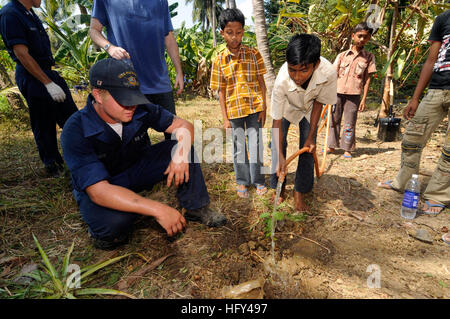 100324-N-8335D-148 Port Blair, India (24 marzo 2010) Mineman marinaio Derek Smith aiuta un ragazzo del Ramakrishna mission, un orfanotrofio a Port Blair, pianta un albero. Smith è stato uno dei 16 velisti assegnati alla miniera contromisure nave USS Patriot (MCM 7) che hanno cancellato la massa per piantare un giardino di melograni, guava e alberi di limone alla missione. Patriot è il primo U.S. Navy navi da guerra per visitare Port Blair e sarà in conduzione l'addestramento militare con la Marina militare indiana. (U.S. Foto di Marina di Massa lo specialista di comunicazione 1a classe Richard Doolin/RILASCIATO) Navy US 100324-N-8335D-148 Mineman marinaio Derek Foto Stock