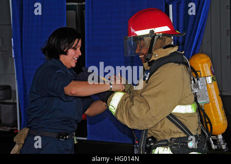Un vigile del fuoco per il controllo dei danni dimostra le procedure antincendio a un visitatore durante una crociera di una giornata in famiglia a bordo della USS George Washington (CVN 73), fornendo informazioni sulla vita di bordo e sulle operazioni di emergenza. Foto Stock