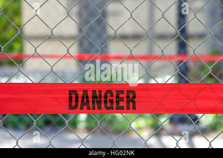 Rosso riflettente barriera di pericolo nastro attraverso una catena collegamento recinto per tenere i pedoni al di fuori della zona di costruzione Foto Stock
