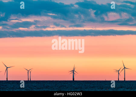 Inghilterra, Herne Bay. Le turbine eoliche, Kentish Flats per centrali eoliche nel Canale della Manica a day break, arancione chiaro cielo sull'orizzonte con le nuvole scure sopra. Foto Stock