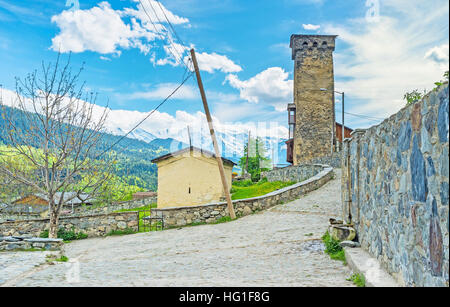 La vecchia strada di pietra con una piccola cappella del cimitero vecchio e torre Svan su sfondo, Mestia, Svaneti superiore, Georgia. Foto Stock