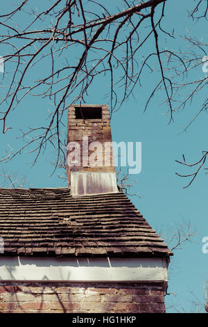 Dettagli di un vecchio camino e tetto a spiovente con scandole di cedro su una vecchia casa di mattoni. Foto Stock