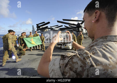 Un U.S. Marine acquisisce una foto della U.S. E la Marina militare australiana membri come essi pongono tenendo premuto 'Australia sportivo della bandiera' sul ponte di volo dell'assalto anfibio nave USS Peleliu (LHA 5) durante l'Orlo del Pacifico (RIMPAC) Esercizio 2014 come i partecipanti si riuniranno in formazione dopo una foto esercizio (PHOTOEX). Ventidue nazioni, 49 navi e sei sommergibili, più di 200 aerei e 25.000 personale partecipano RIMPAC esercizio dal 26 giugno al 1 agosto, in e intorno alle Isole Hawaii e la California del Sud. Il più grande del mondo marittimo internazionale esercitazione RIMPAC fornisce Foto Stock