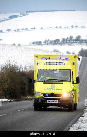 Ambulanza sulla strada di un paese circondato dalla neve in inverno. Foto Stock