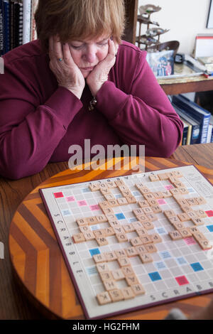 Attraente donna matura studiando la sua prossima mossa in un gioco SCRABBLE. Downers Grove Illinois IL USA Foto Stock