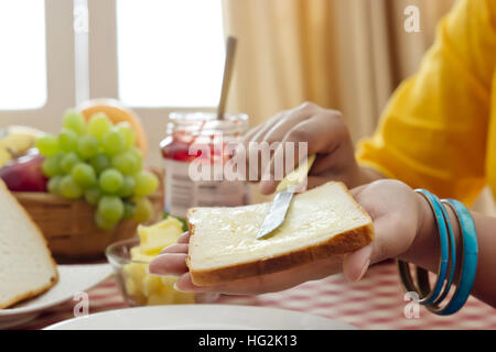 Donna diffusione di burro sul pane Foto Stock